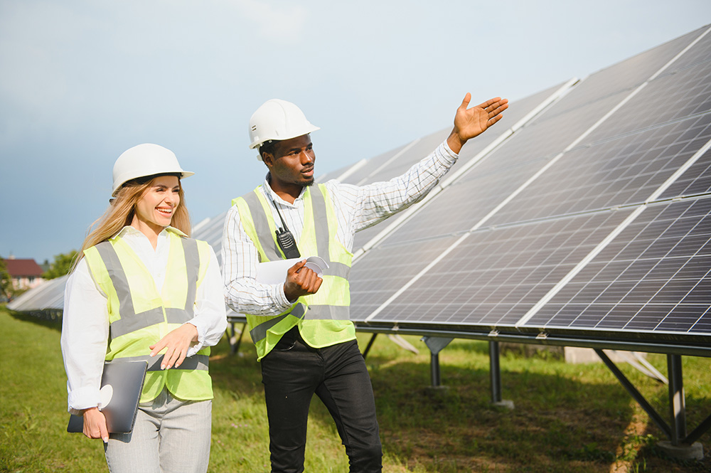 Zwei Fachkräfte in Schutzkleidung und Helmen prüfen Solaranlagen im Freien – Startime Services vermittelt qualifiziertes Personal für Photovoltaik, Windkraft und Biogas.